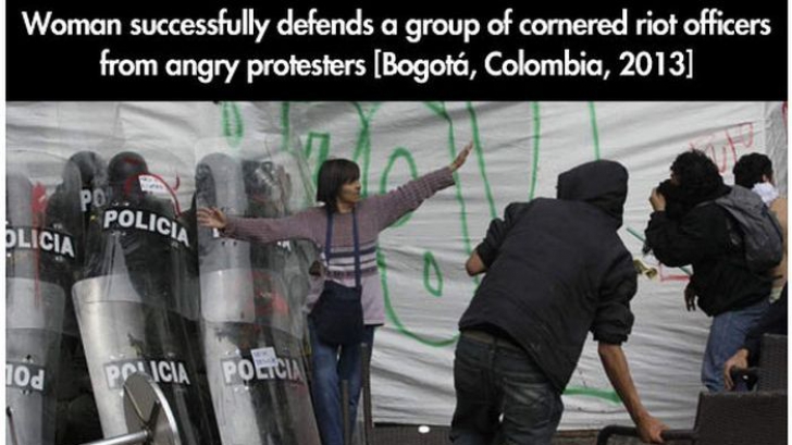 O femeie îi apără pe poliţişti de protestatarii furioşi, Bogota, 2013