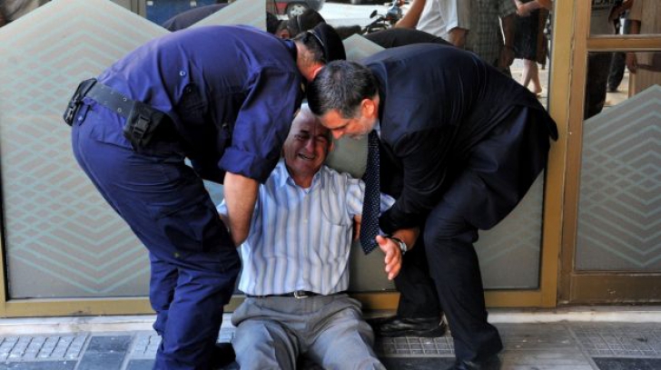 Tragedia greacă în imagini. Fotografia neputinței. Un bătrân plânge, deznădajduit, în fața băncilor 
