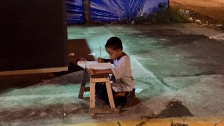 Acest micuț își făcea temele chiar în stradă, la lumina unei vitrine