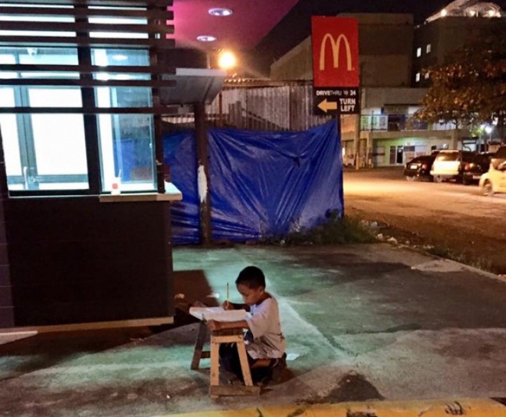 Acest micuț își făcea temele chiar în stradă, la lumina unei vitrine