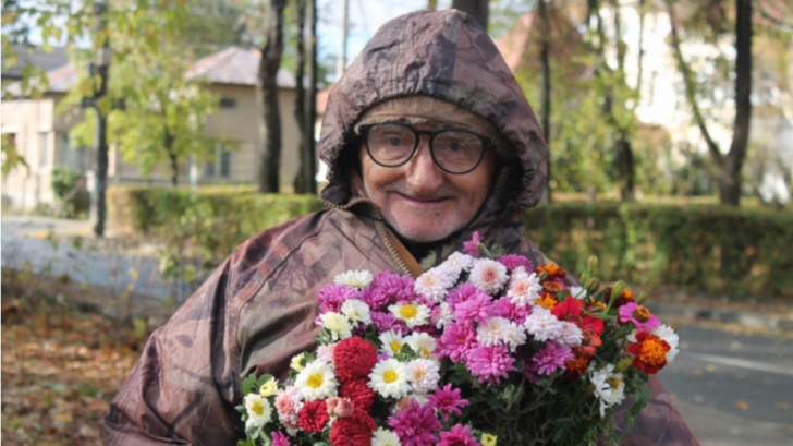 Acest bărbat vinde flori în Parcul Copou, în Iaşi. Pe pancartă a scris mesajul care aduce zâmbete