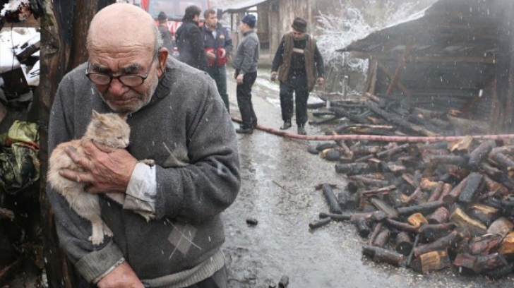 În lacrimi, bătrânul strânge pisica la piept, după ce i-a ars casa. Imaginea face înconjurul lumii