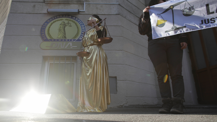 Protest la sediul DNA! O femeie îmbrăcată în auriu, legată la ochi, întruchipează Justiția oarbă