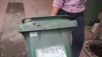 O femeie a fost surprinsă în timp ce transporta cadavrul unui bărbat într-un tomberon