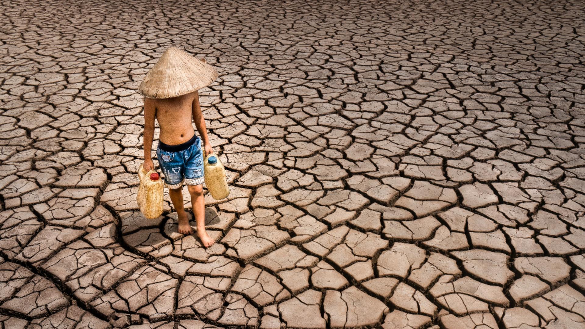 Un băiețel fotografiat adunând ultimele picături de apă. Sursa foto: Profi Media