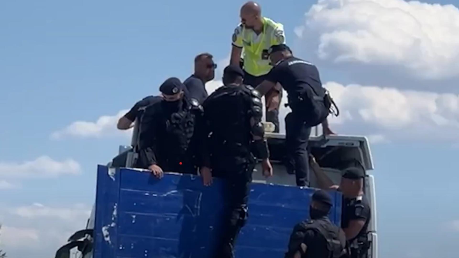 Jandarmi cocoțați pe cabina camionului ca să dea jos protestatarul. Foto/Captură video