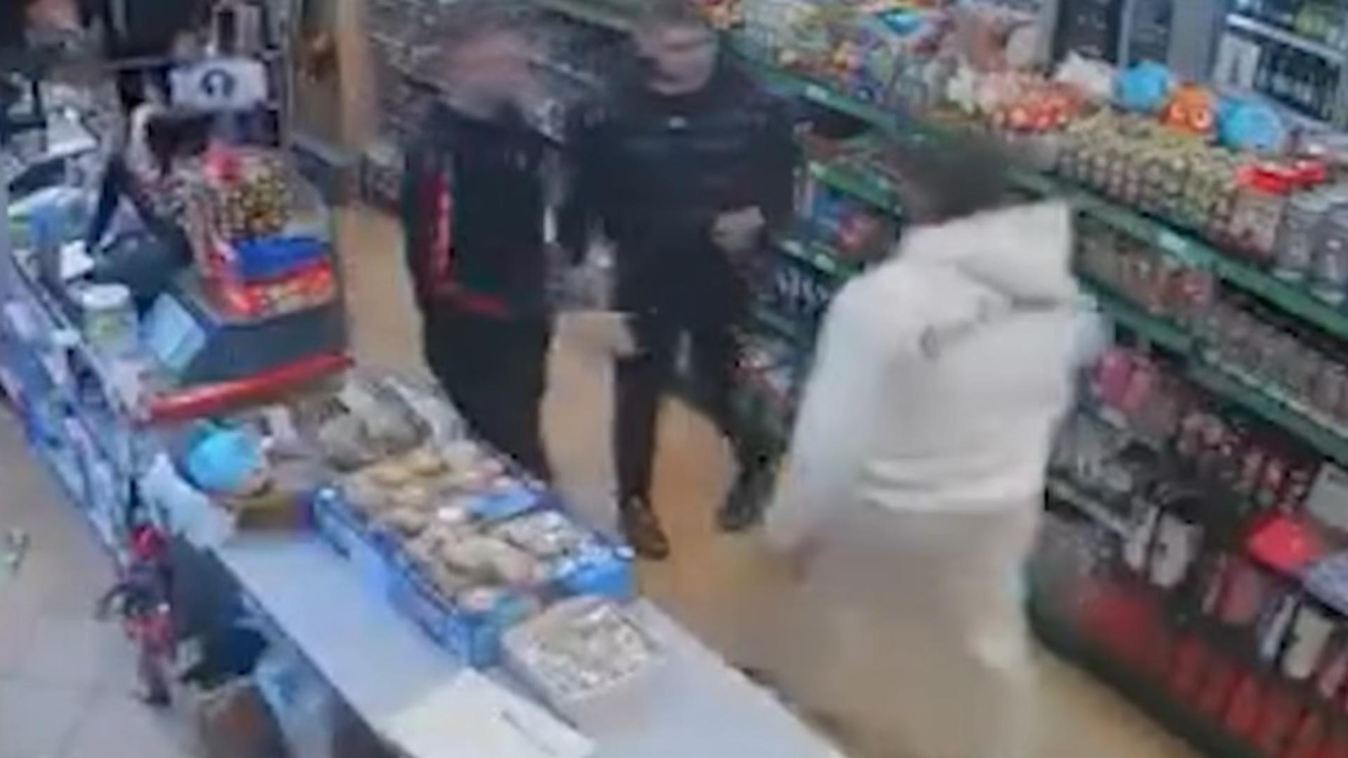 Agresorul (în alb) a fost încătușat de polițiști după ce a atacat femeia. Foto/Captură video